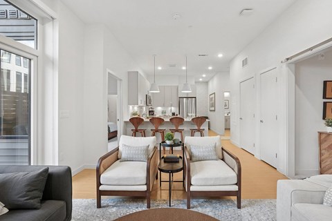 A living room with a black couch, a white chair, and a brown coffee table.