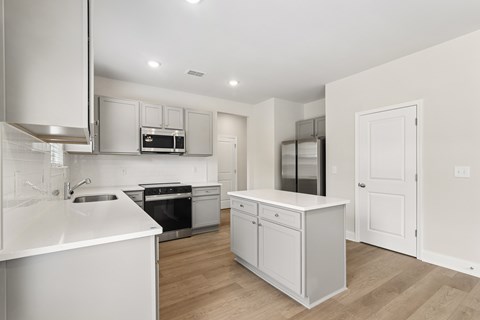 A modern kitchen with white cabinets and appliances.