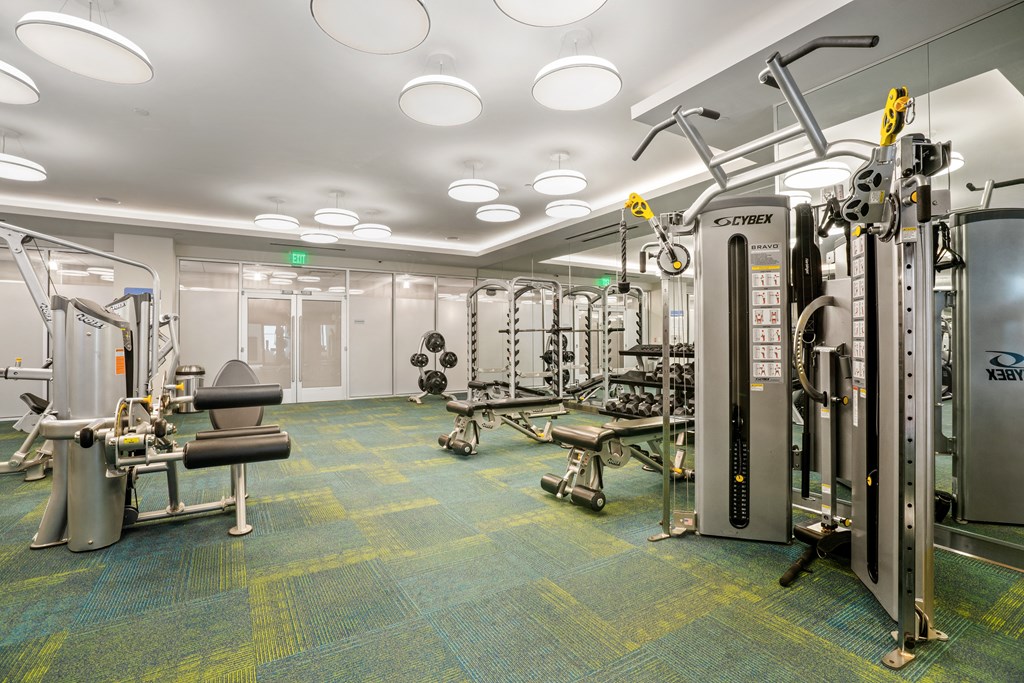 a spacious fitness room with cardio equipment and weights