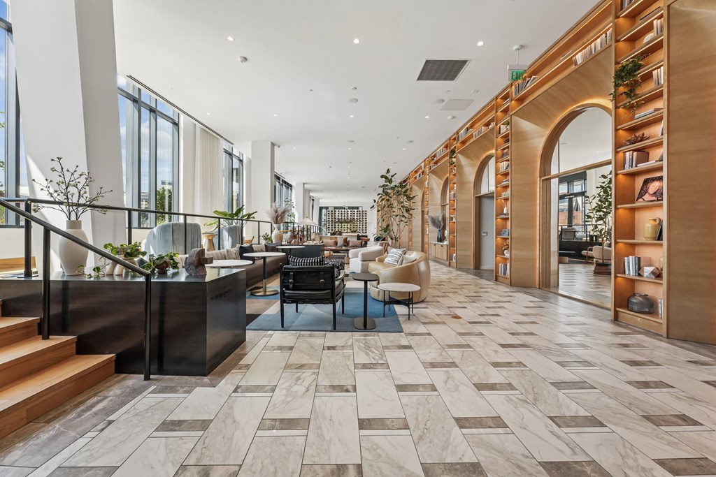 A spacious lobby with a marble floor and a staircase with a metal railing.