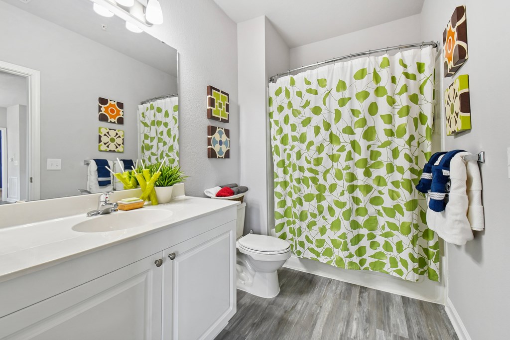 A bathroom with a white sink, toilet, and a green shower curtain.