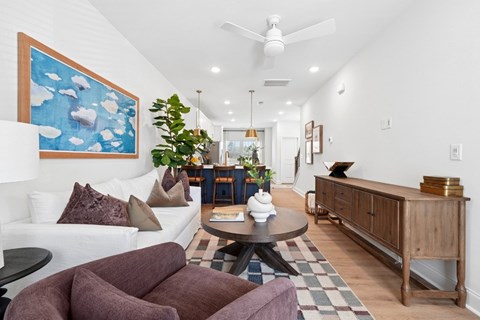 A living room with a white couch and a painting on the wall.