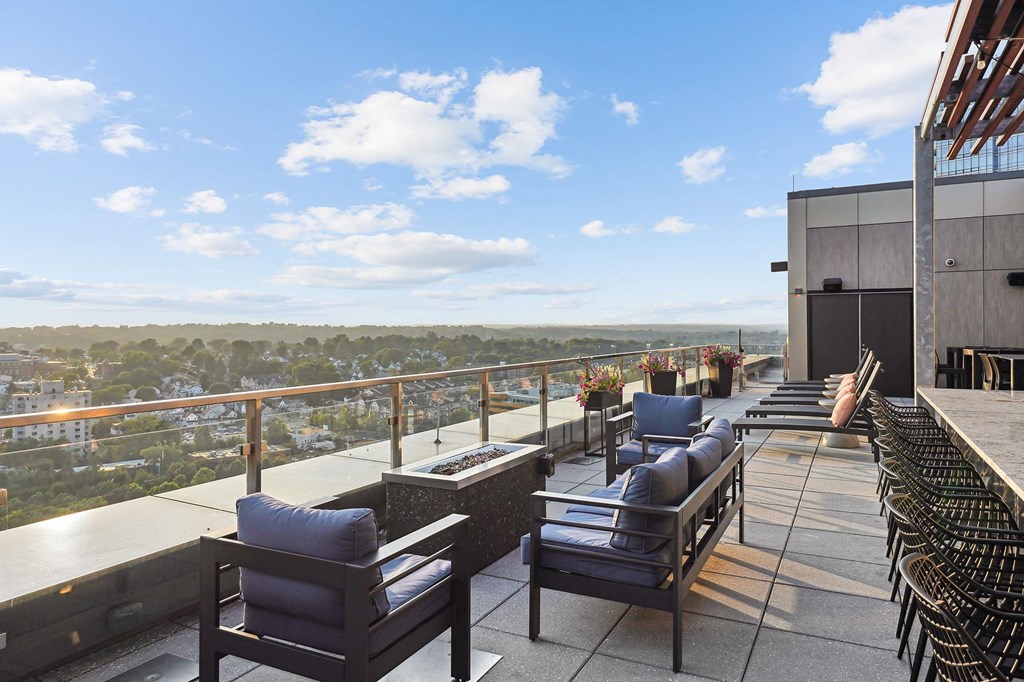 a rooftop terrace with chairs and tables overlooking a city