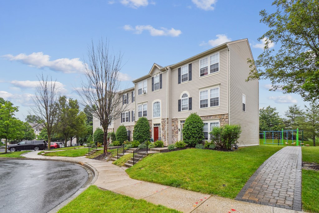 A residential building with a red door and a green fence in front.