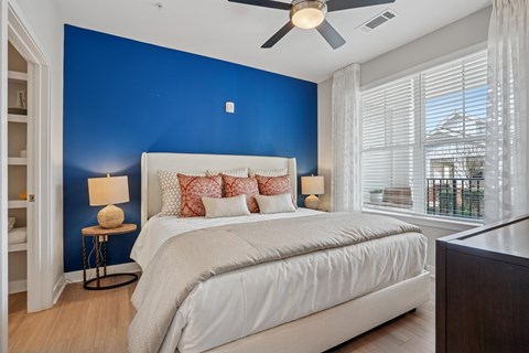 A bedroom with a white bed and a ceiling fan.