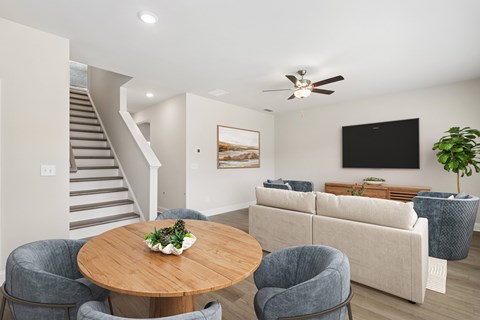 A living room with a grey couch, a wooden table and a staircase.