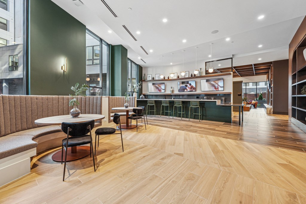 a communal area with tables and chairs and a kitchen in the background