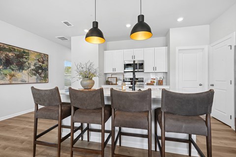 A kitchen with a table and chairs in front of it.