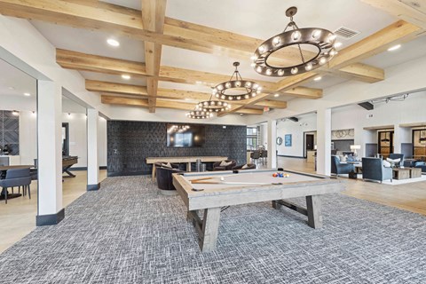 A billiard table is in the middle of a room with a wooden ceiling and a grey carpet.