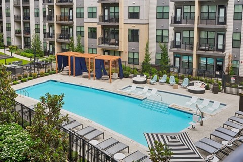 A large swimming pool surrounded by lounge chairs and umbrellas.