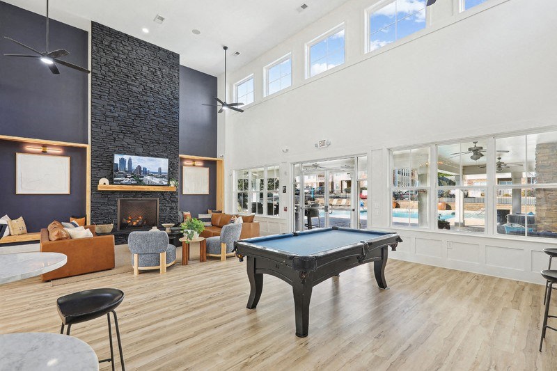 A black pool table is in the middle of a room with a fireplace and a television.