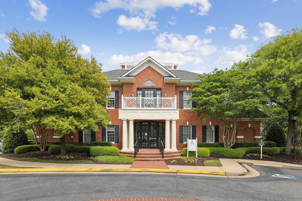 the front of a brick house with a balcony and trees