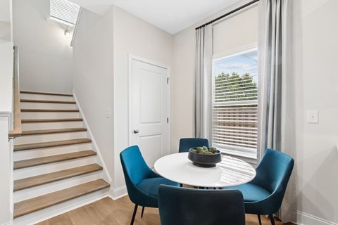 A dining room with a round table and four chairs.