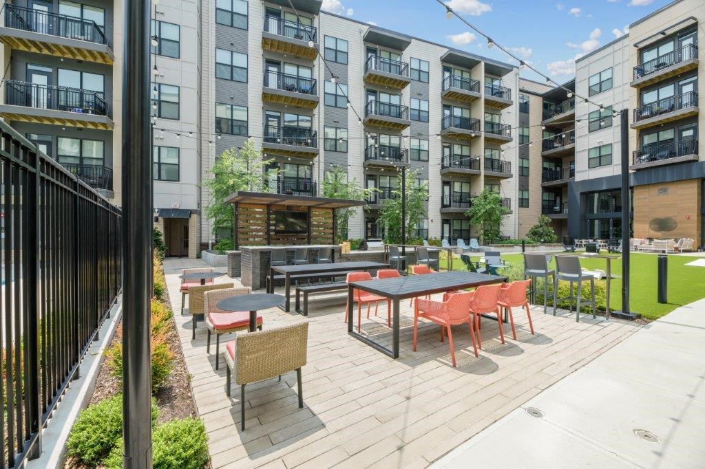 a patio with tables and chairs in front of an apartment building