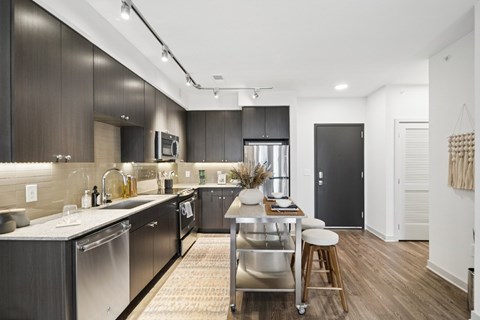 A modern kitchen with dark wood cabinets and stainless steel appliances.