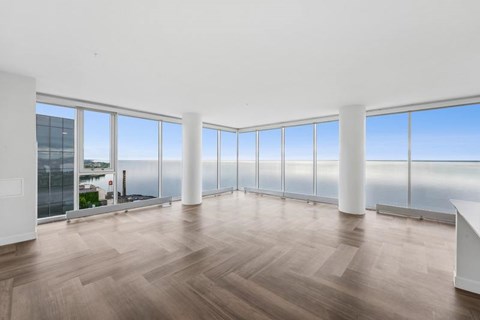 A large empty room with wooden floors and large windows overlooking the city.