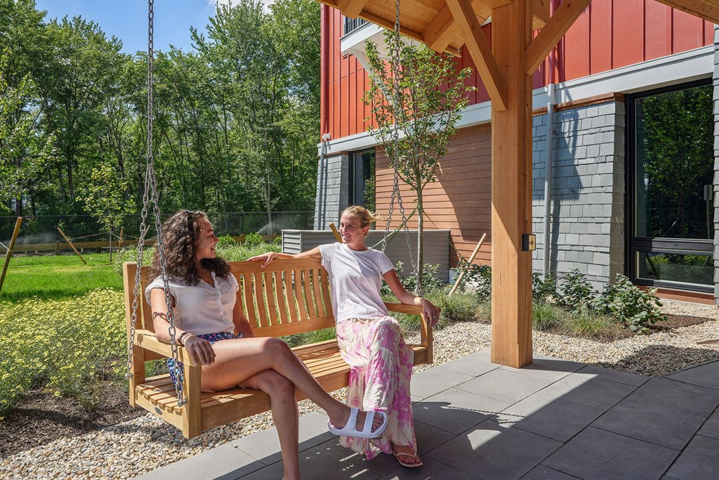 two women sitting on a bench on a porch