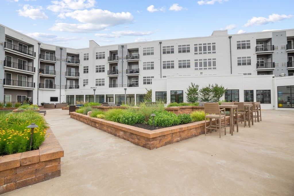 a courtyard with tables and chairs and a large white building in the background