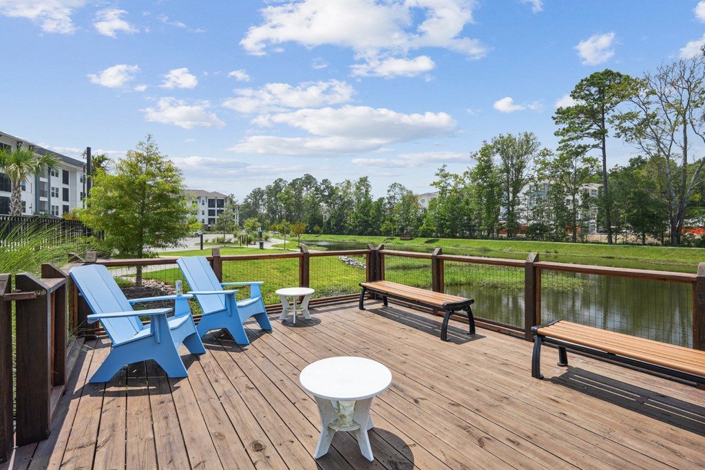 a deck with chairs and a table overlooking a body of water