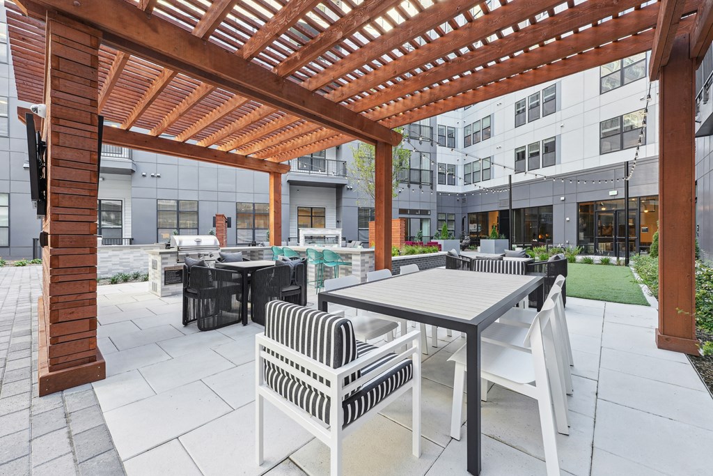 a patio with tables and chairs and a wooden pergola