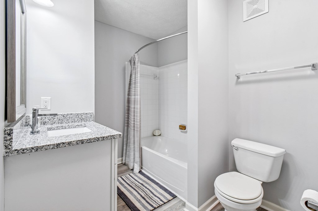 A white bathroom with a toilet, sink, and bathtub.