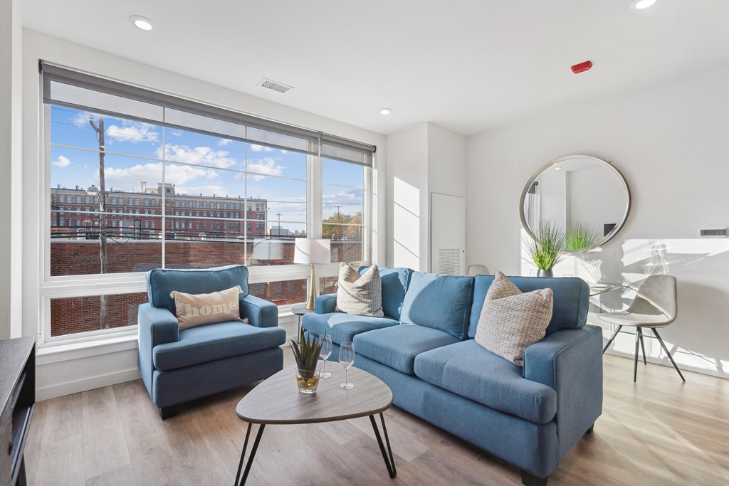 a living room with a blue couch and a coffee table and a large window