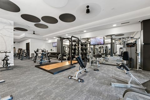 A spacious gym with a variety of equipment and a flat screen TV mounted on the wall.