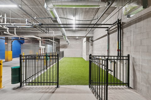 A gated entrance to a building with a green artificial turf area.