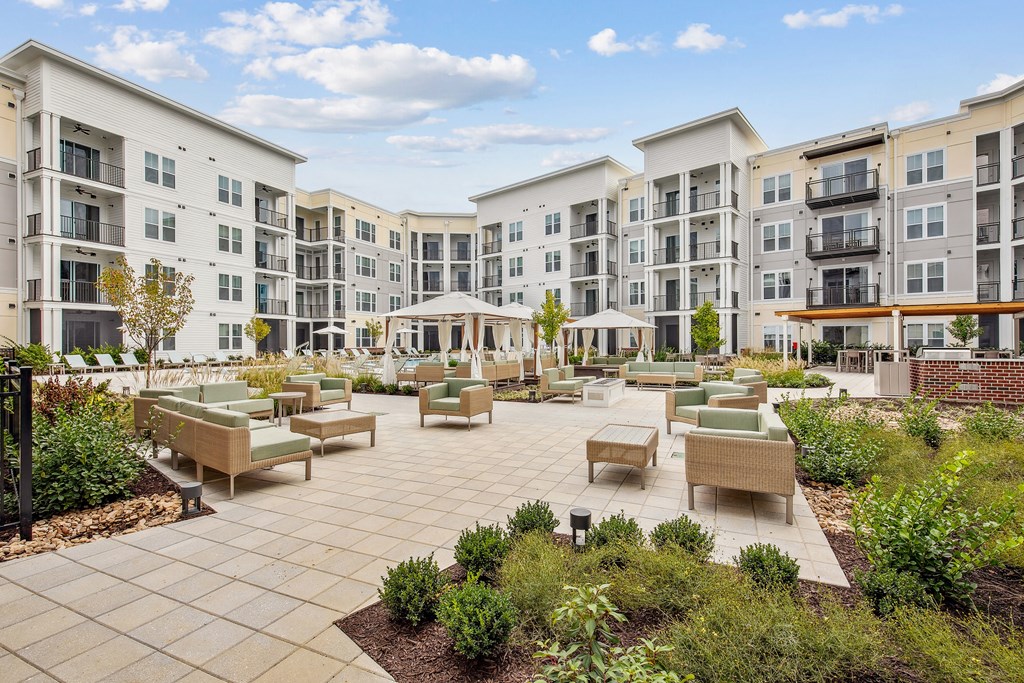 an open courtyard with seating and tables in front of an apartment building