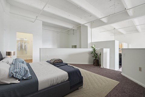 a bedroom with a bed and a rug in a white room
