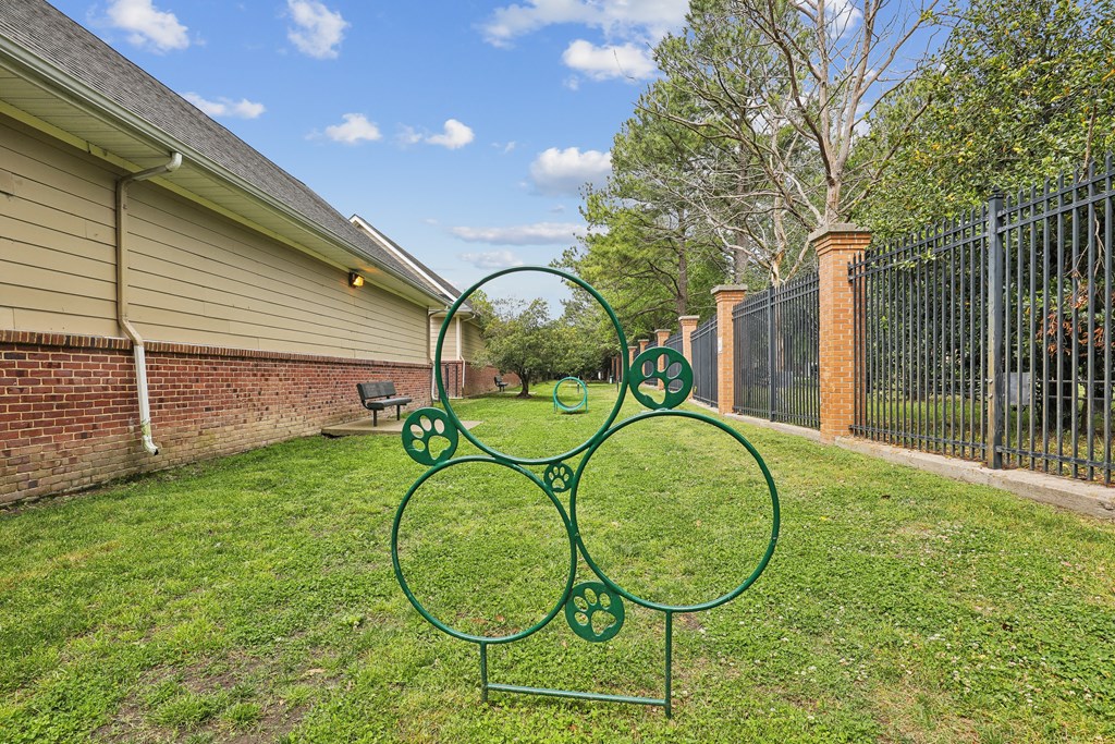 a green sculpture in the yard of a house with a fence