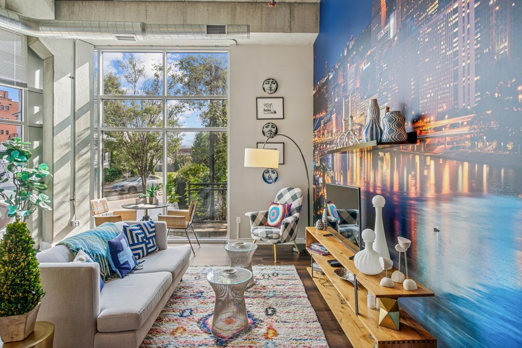 A living room with a large window and a cityscape mural on the wall.