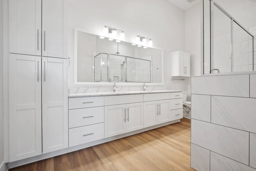 a large white bathroom with a large mirror and white cabinets