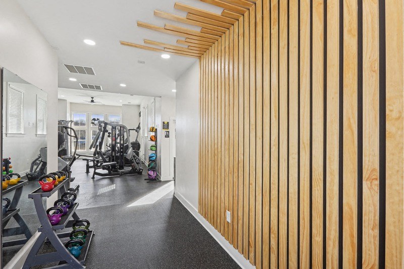 A gym with a row of exercise equipment on the left and a wood panelled wall on the right.