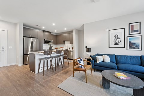 A modern living room with a blue couch and a dining table with chairs.