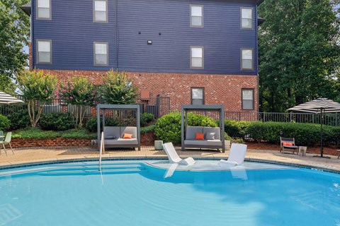 A blue swimming pool in front of a brick building.