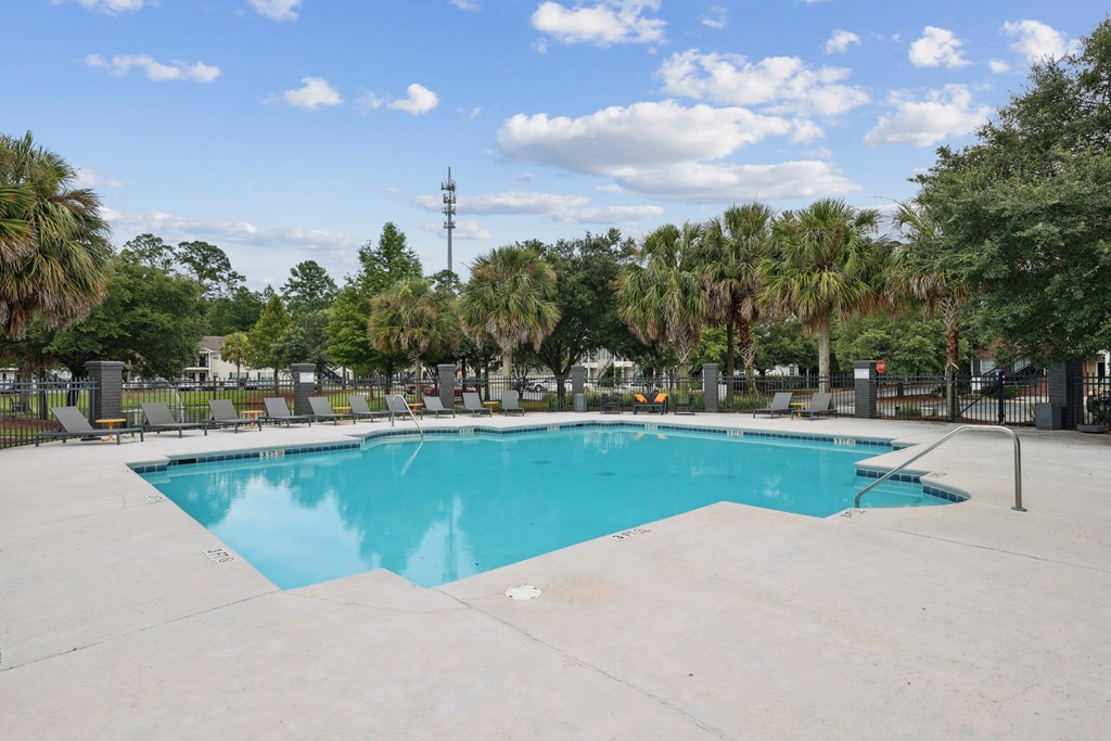 A large swimming pool surrounded by palm trees and lounge chairs.