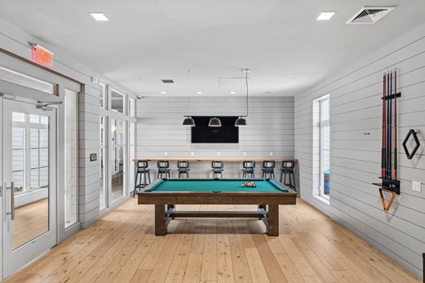 A room with a pool table and a tv.
