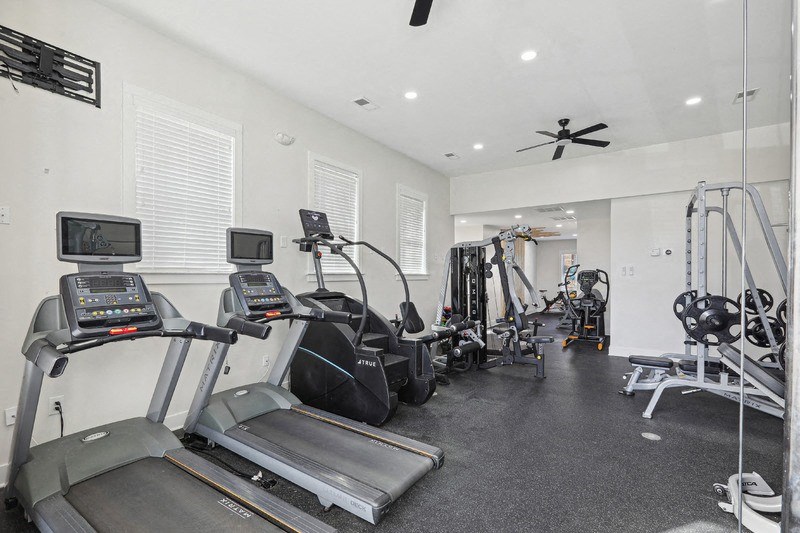 A spacious home gym with treadmills, elliptical machines, and other exercise equipment.