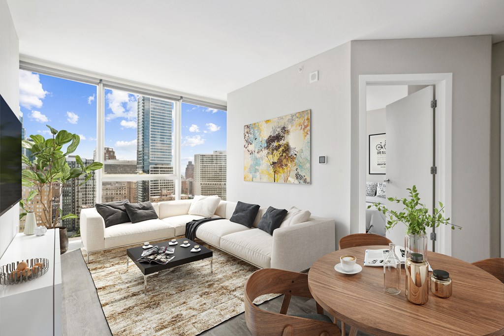 A living room with a couch, a coffee table, and a large window overlooking the city.