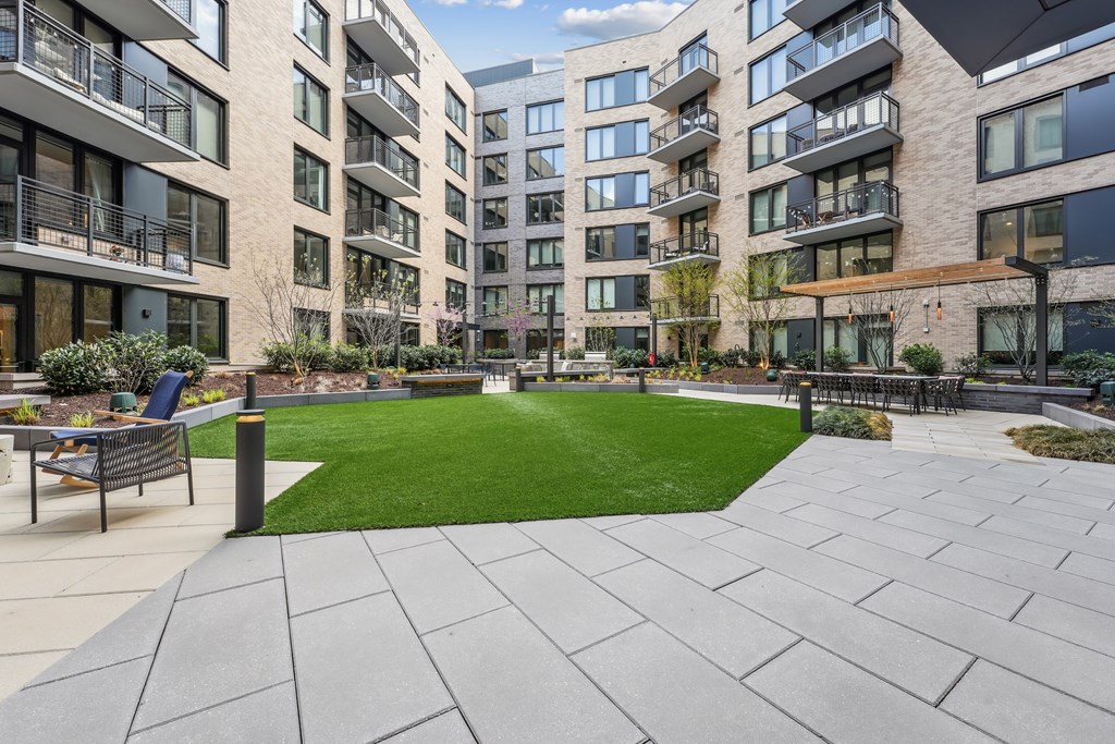 A courtyard with a grassy area and paved walkway surrounded by apartment buildings.