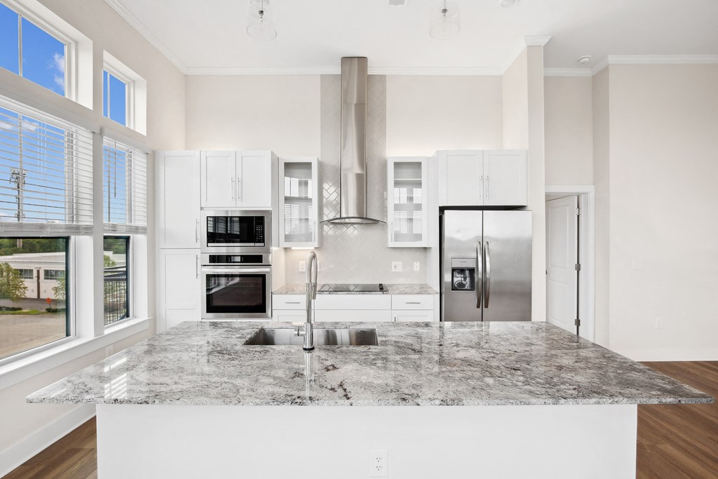 a large kitchen with white cabinets and a marble counter top
