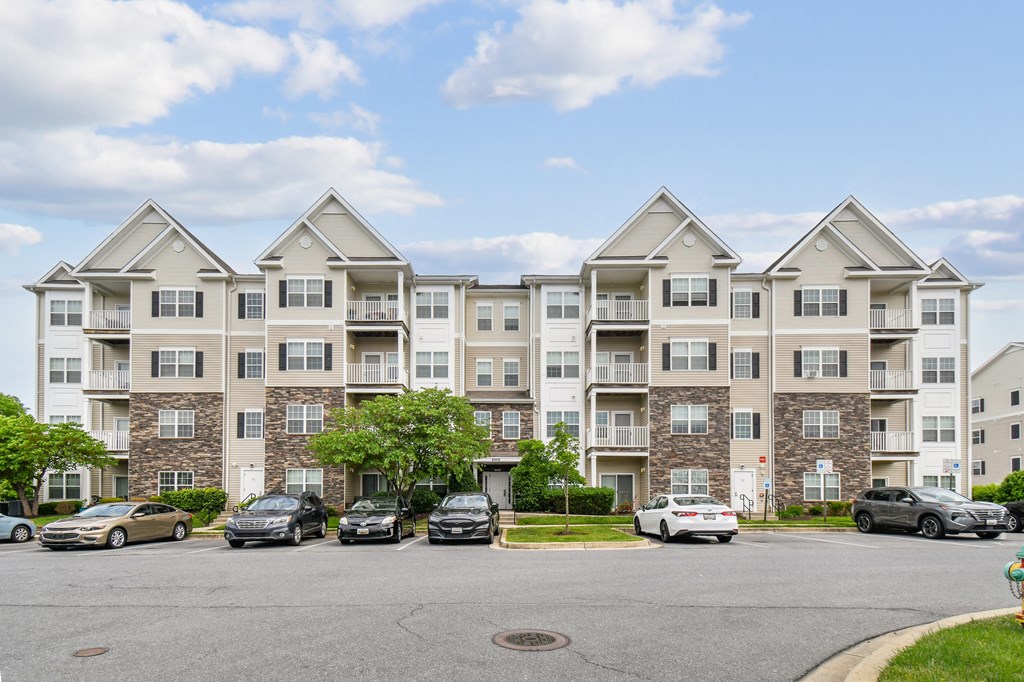 A large apartment building with cars parked in front.