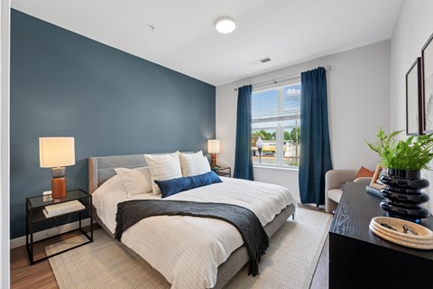 A bedroom with a large bed and a window with blue curtains.