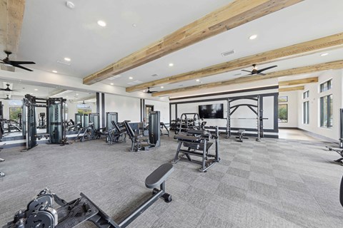 A spacious gym with a variety of equipment and a large mirror on the wall.