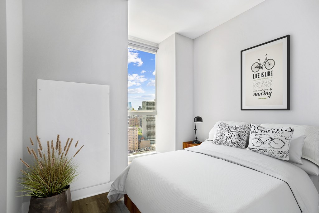 A bedroom with a large bed and a framed picture on the wall.