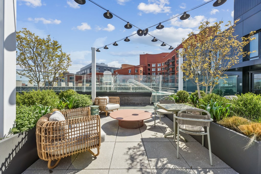 A patio with a table, chairs, and plants.