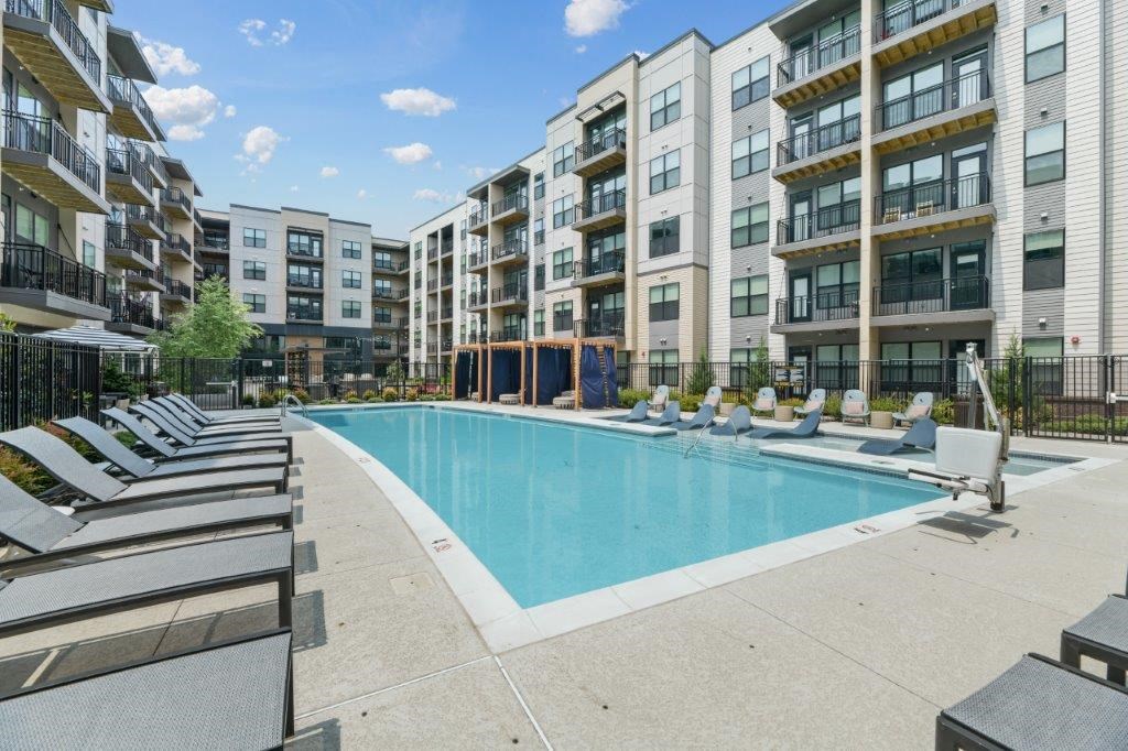 a swimming pool with chaise lounge chairs in front of an apartment building