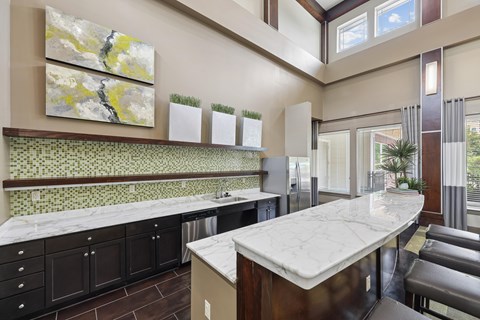 A kitchen with a marble countertop and black cabinets.