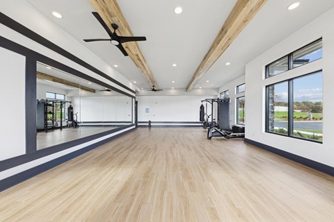 A spacious room with wooden floors and a ceiling fan.